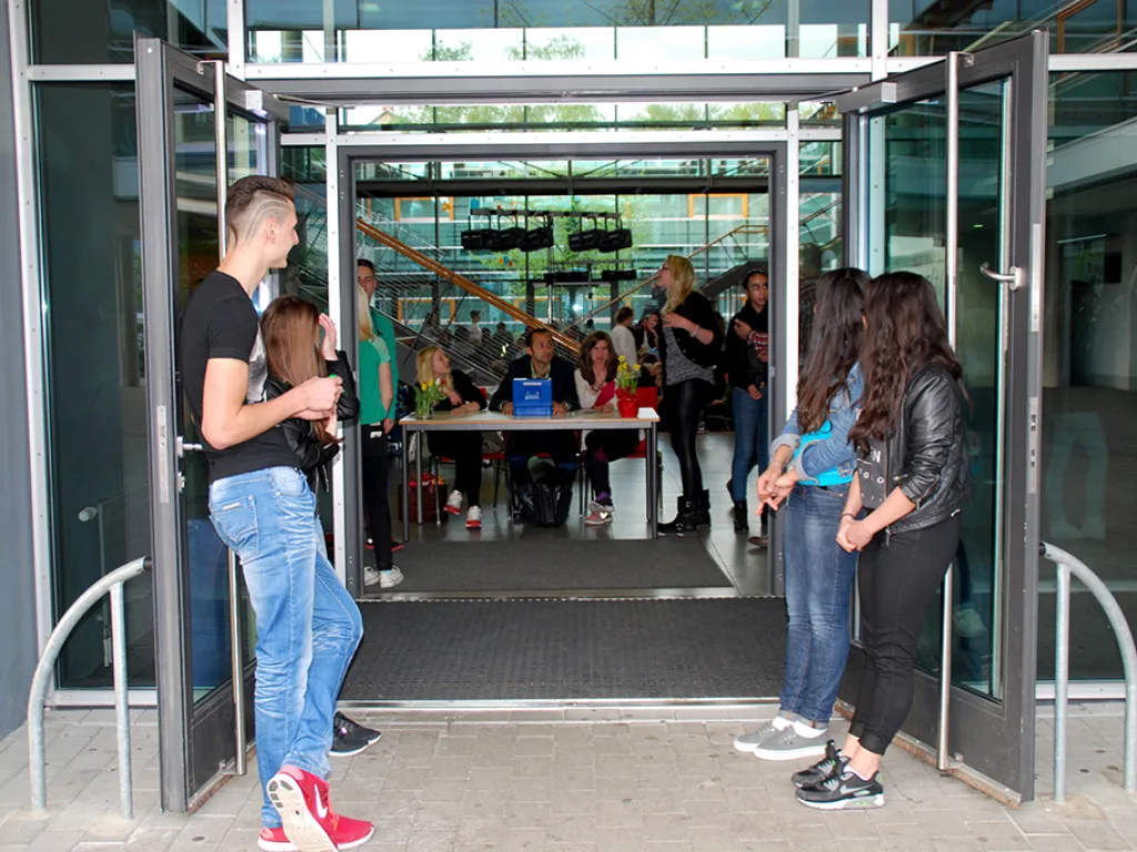 Besucher kommen durch die Eingangstüren ins Foyer.